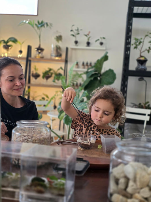 A child carefully placing terrarium materials with planting tweezers
